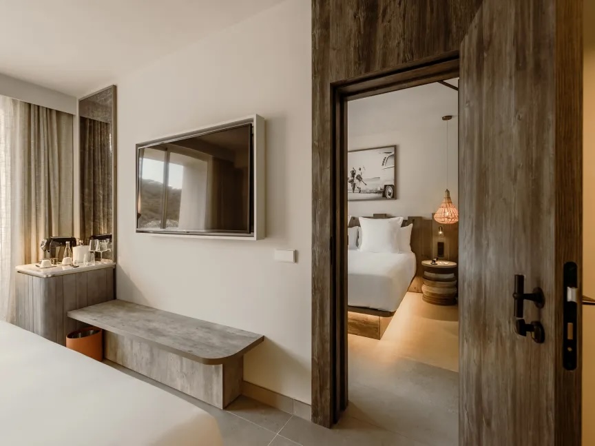 tv unti hanging on the wall with coffee station next to it and a bed showing through the door frame next to the tv