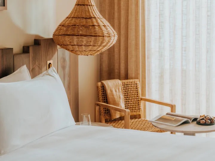 close up of bed with chair next to it and ceiling light hanging over it