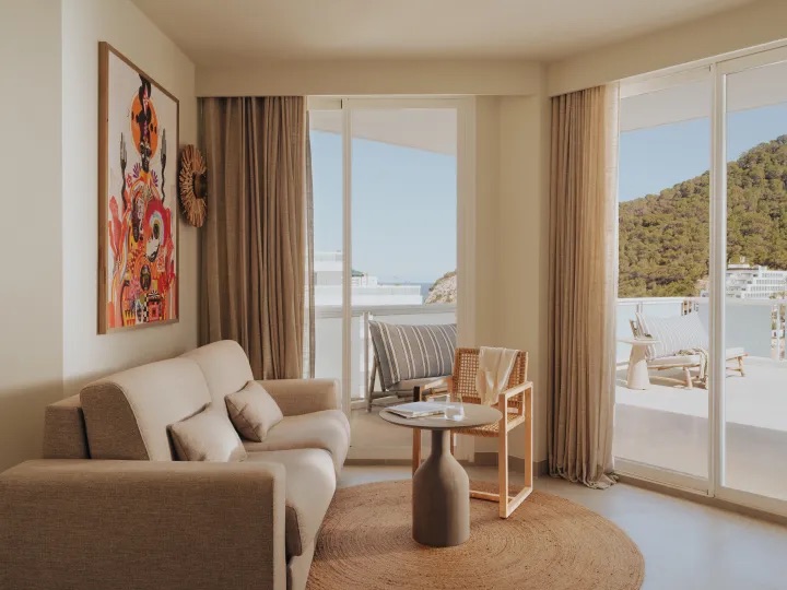 living room of the hotel room with a large couch and a chair around the coffee table with a large window showing the vue