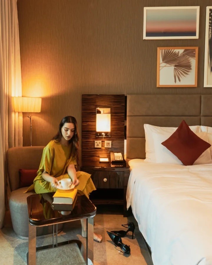 woman sitting next to an empty bed having a tea
