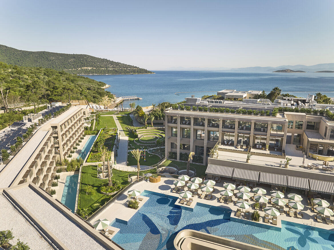 Birdseye view of the pool at Hyde Bodrum with multiple sunloungers and view of hotel