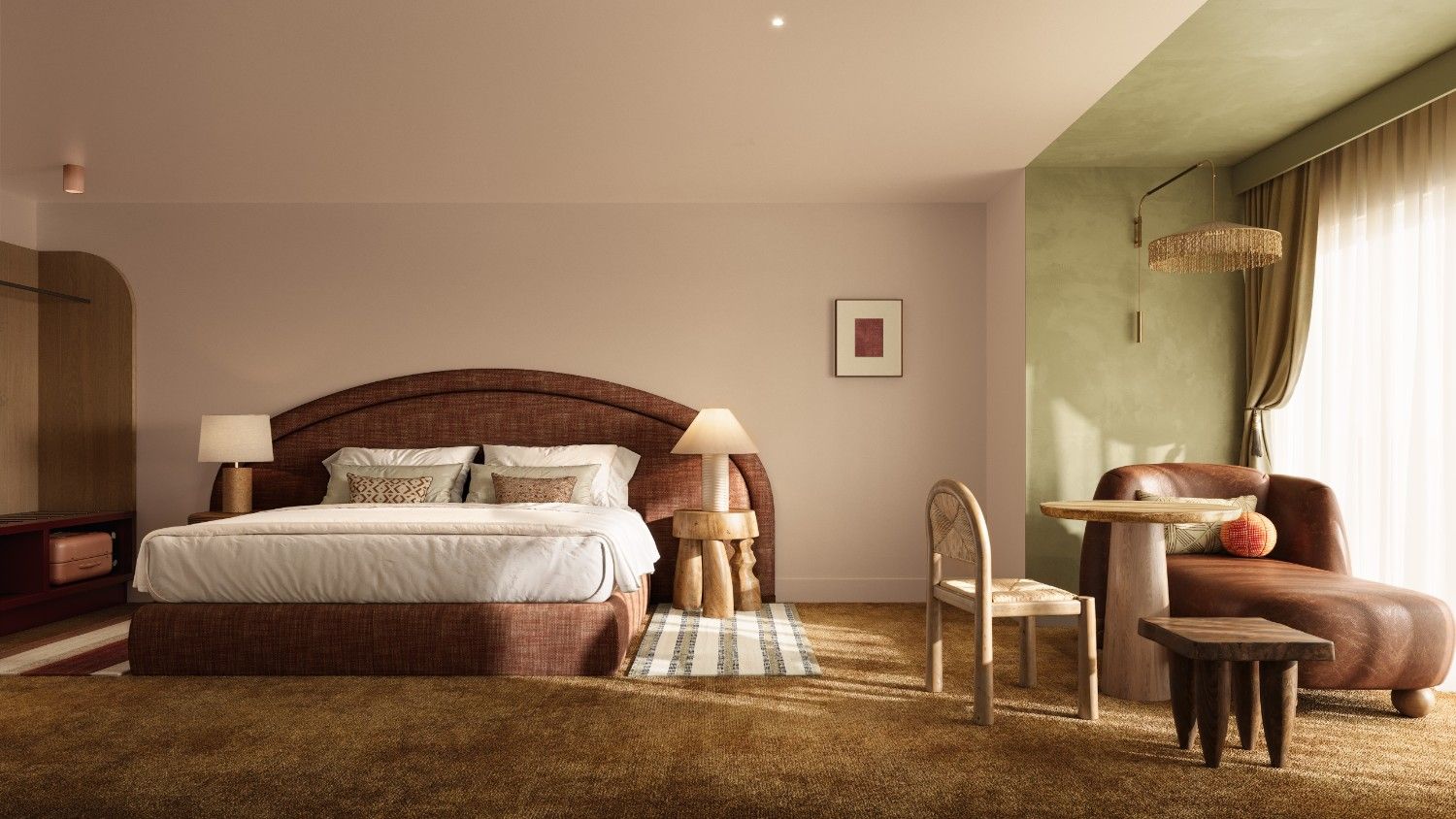 Warm bedroom with a king bed, bedside lamps on wooden stools, and a cozy sitting area by a green accent wall featuring a leather chaise, round table, and chair.