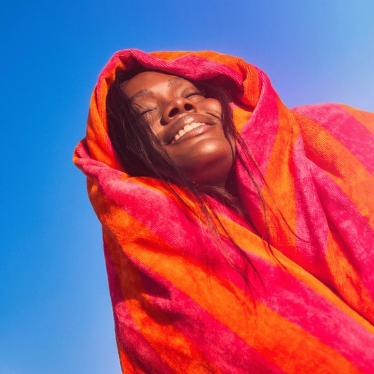 girl wrapped in bright towel with blue sky behind