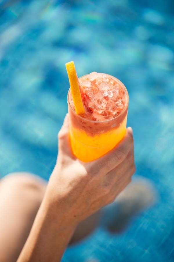 A hand holding an orange cocktail