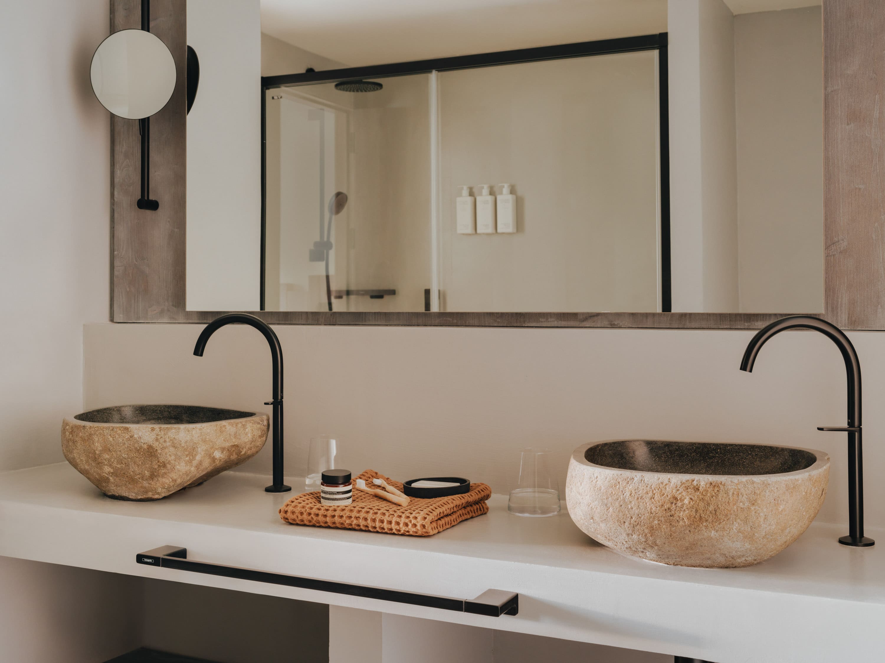 bathroom sink unit with two large sinks, some products sitting between these and a large mirror hanging above it