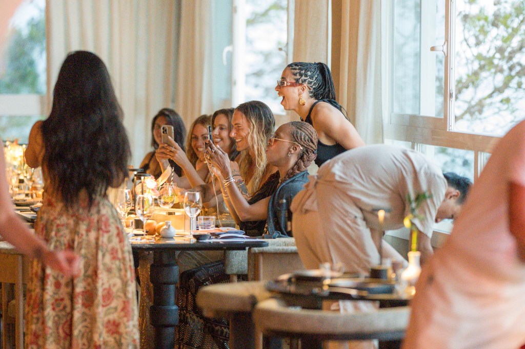 couple of people sitting around a table celebrating with drinks and food