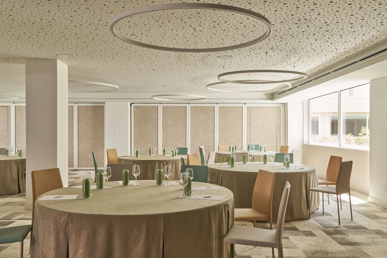 a room with a couple of round table with colour chairs around it