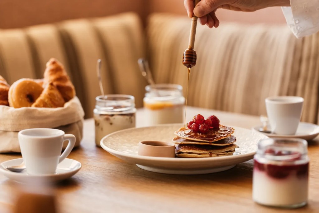 breakfast image with multiple dishes including pancakes and yoghurts
