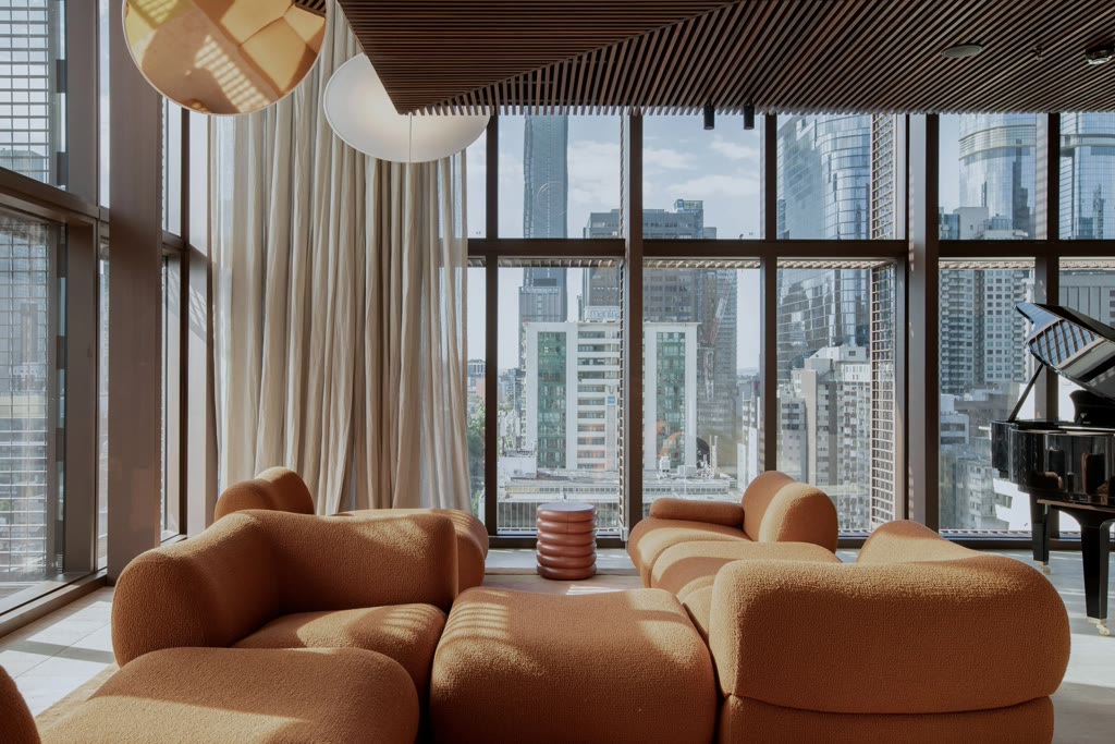Orange couch with a glass wall in the background that shows the city of Melbourne