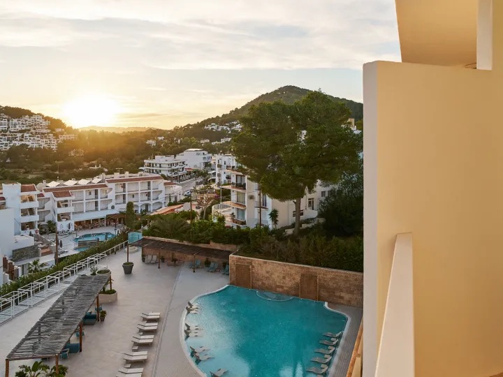 View of the pool with sunbeds next to it and sunrise in the background