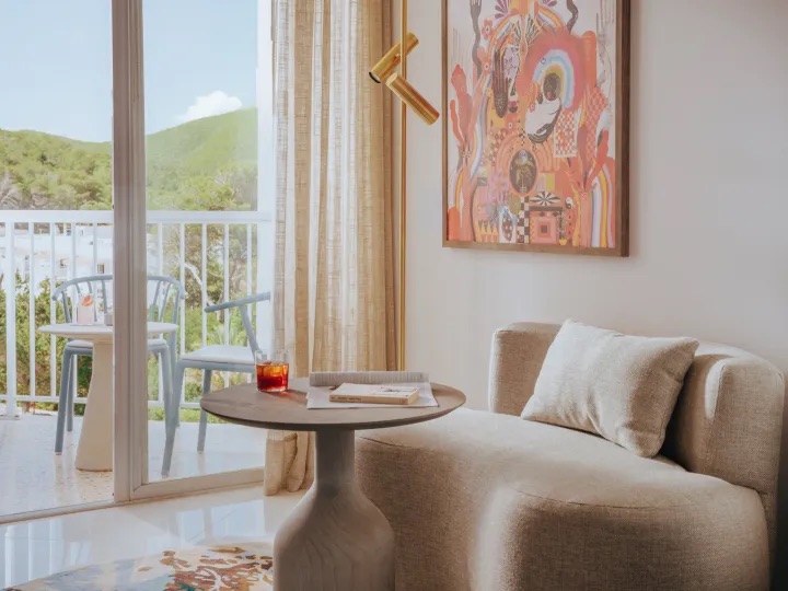 seating area in the hotel room with small couch and table in front of window with view of a hill