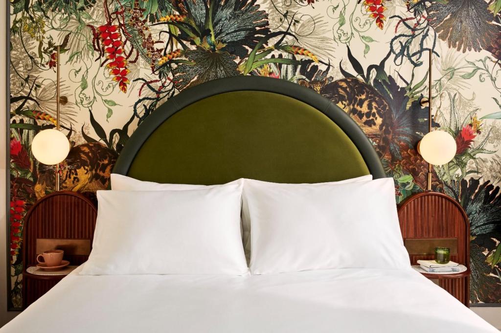 White double bed with green headboard set against tropical themed wallpaper