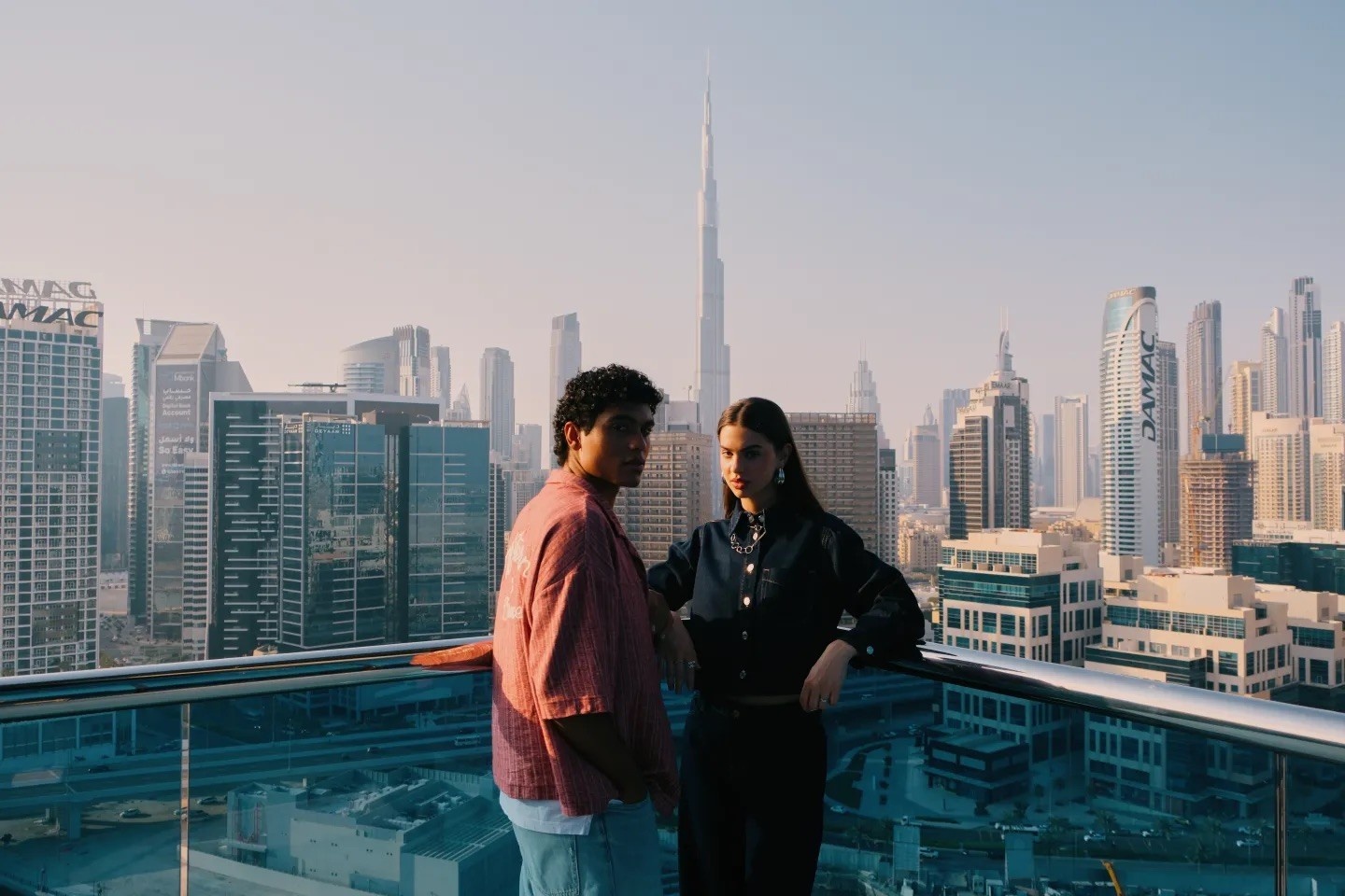 2 people on the balcony of their hotel room showing the Burj Khalifa in the background