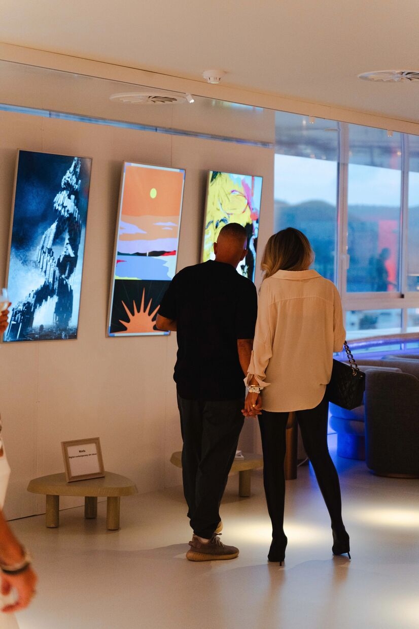 2 men looking at pieces of art hanging on the wall