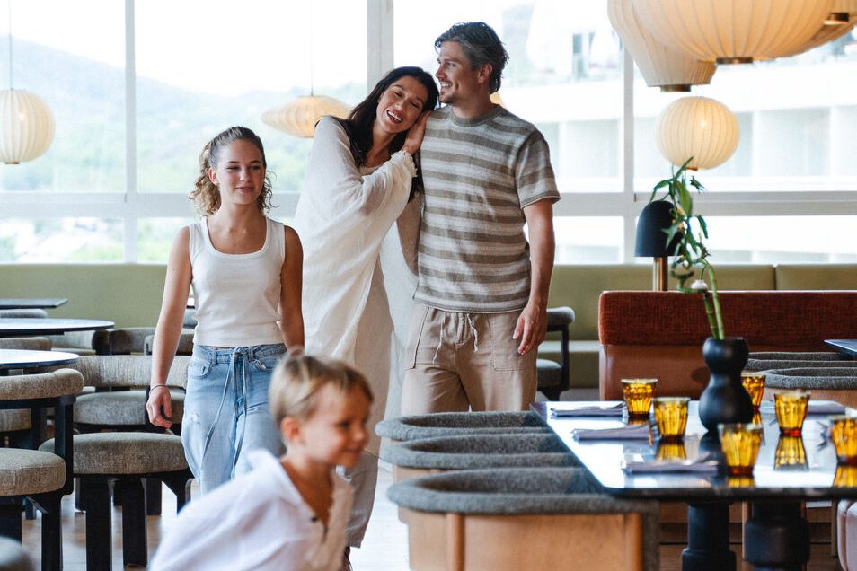 A couple with two children walking around between tables in a restaurant