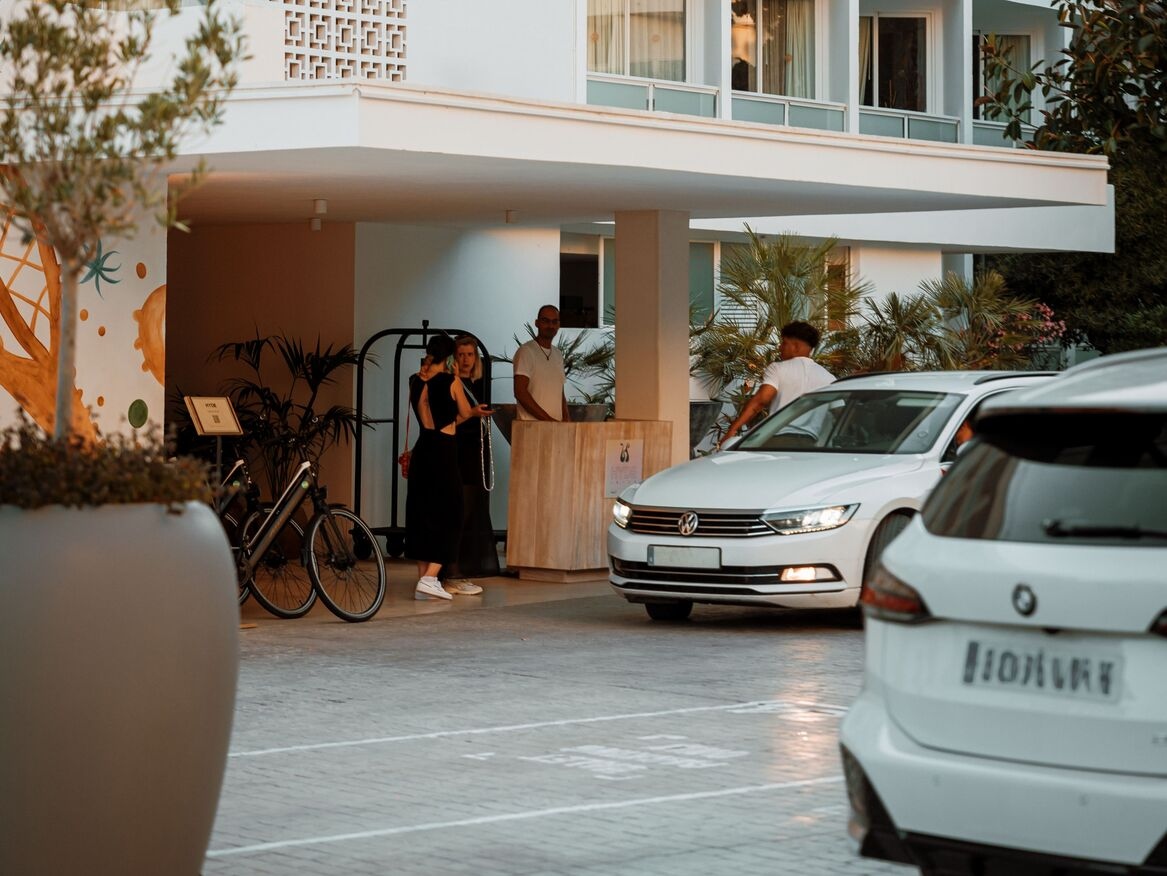 cars parked in front of hotel entrance, including a couple of people working at the hotel