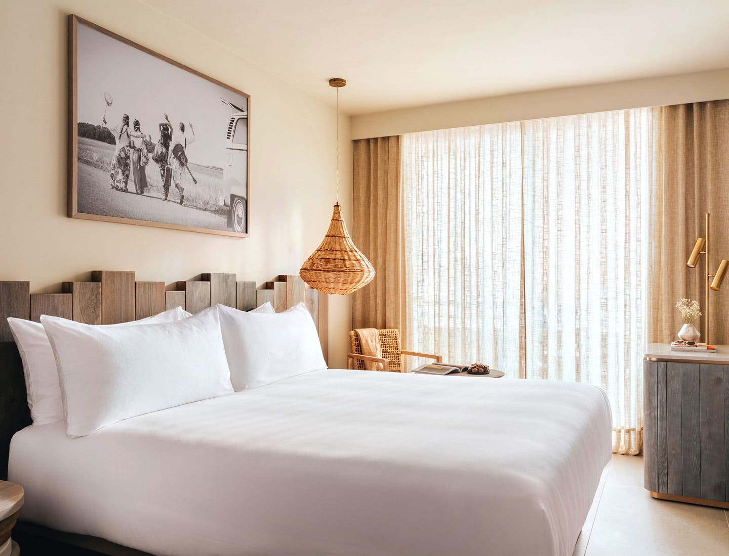 Bed with white bedding with the curtains closed and a picture hanging above it