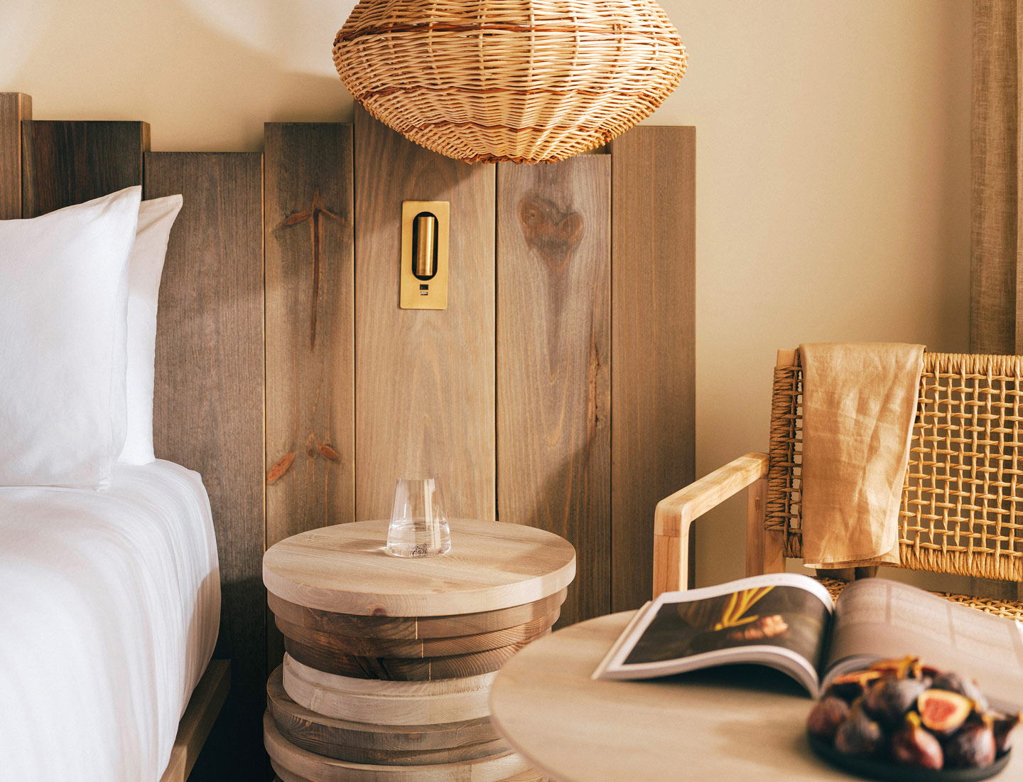 bedside table with a glass of water, a bed next to it and a ceiling light hanging over it