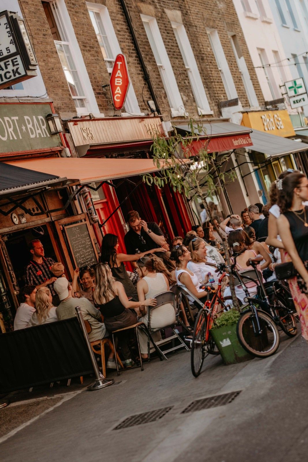 People sitting outside on the terrace of a restaurant, drinking and chatting in the evening sun