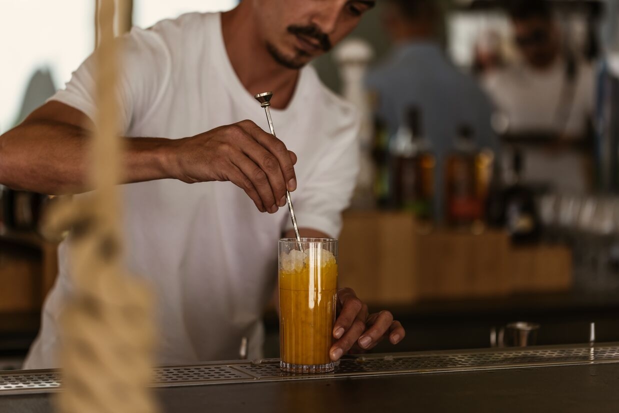 bar man mixing an orange drink with icecubes in it