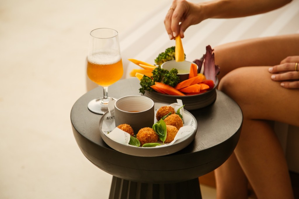 multiple plates of food and a drink on a table with someones hand showing eating the food
