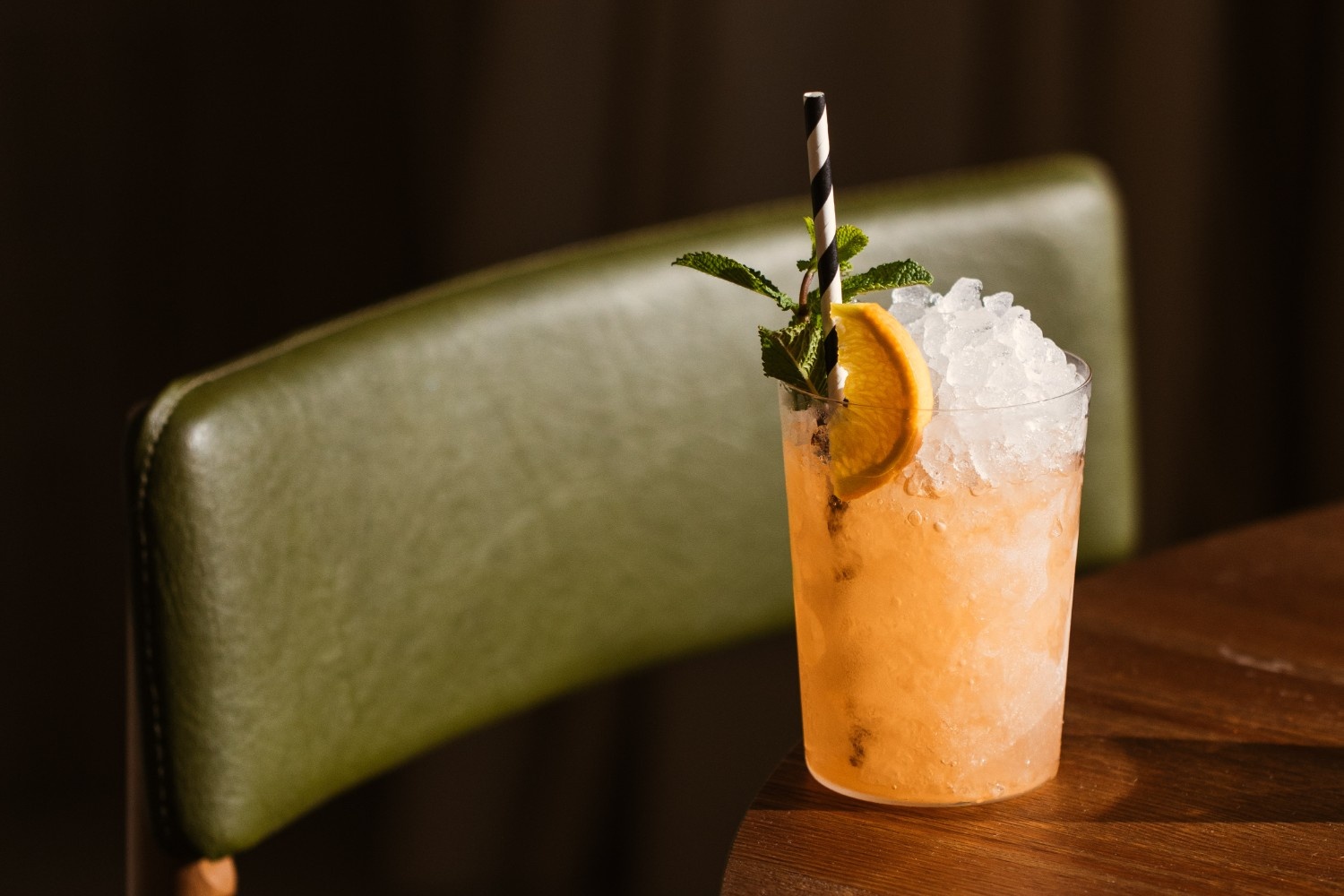 an orange drink on a table with some ice cubes in it