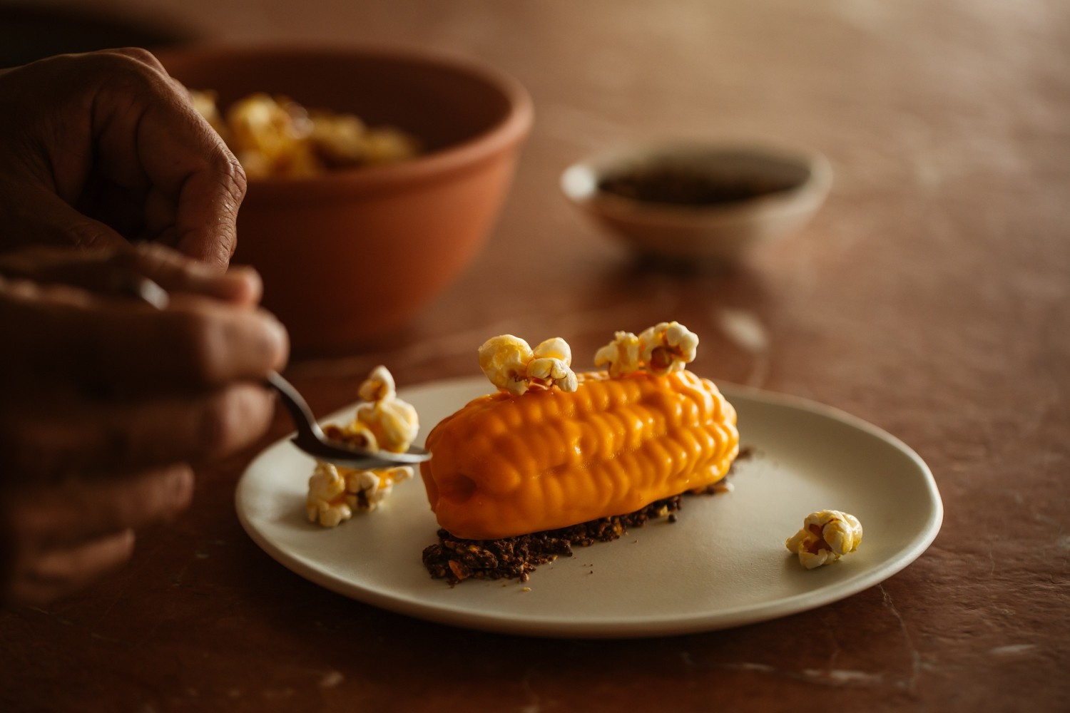 a corn dish on a table with someone's fork digging into it