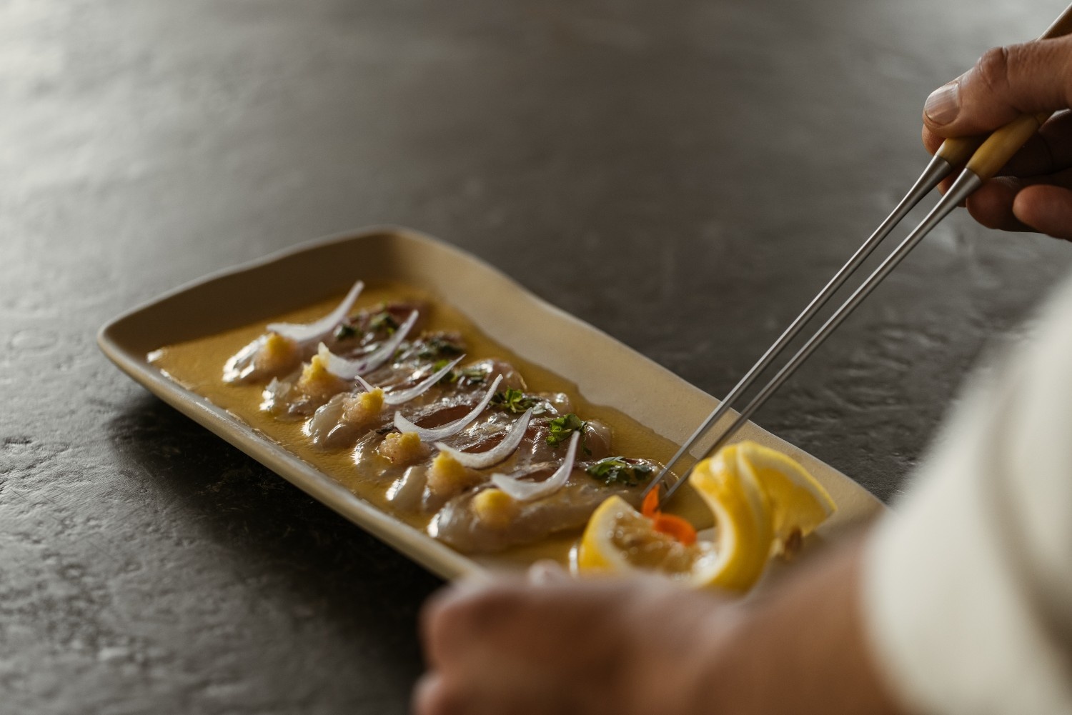 plate of delicate japanese dish with someone still adding the final touches