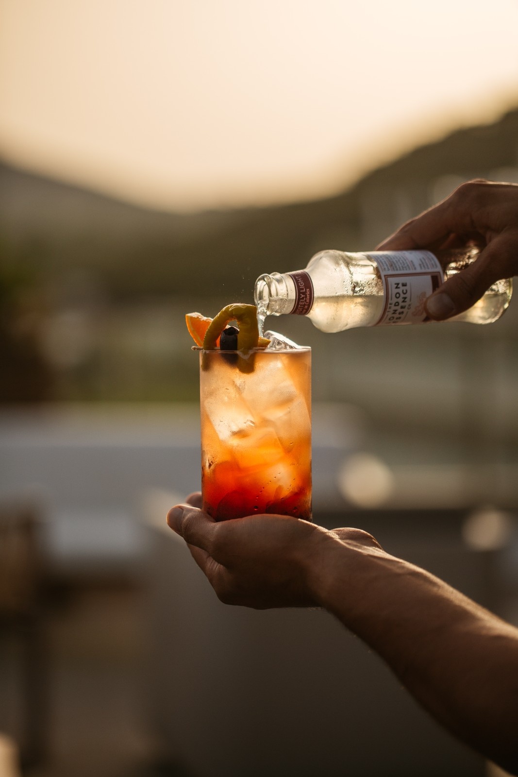 someone holding up a drink and poring something in their glass