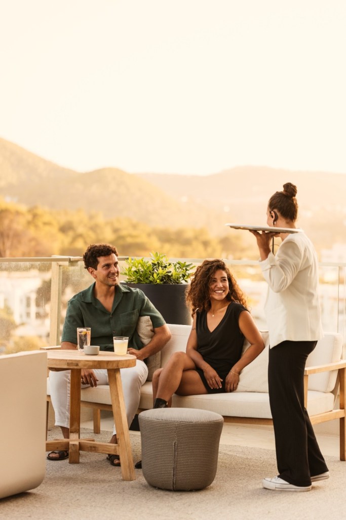 multiple people sitting by a low table being served by a lady