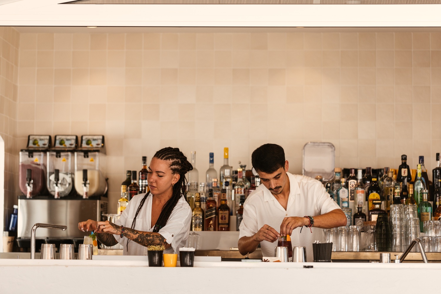 two people behind a bar making drinks