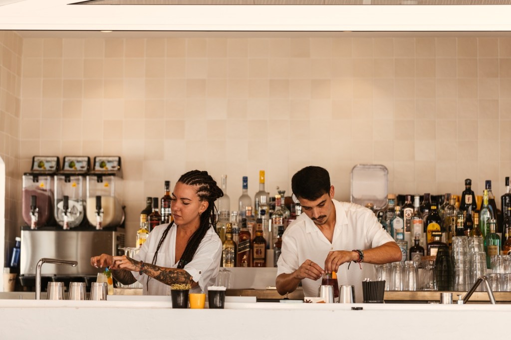 two people behind a bar making drinks