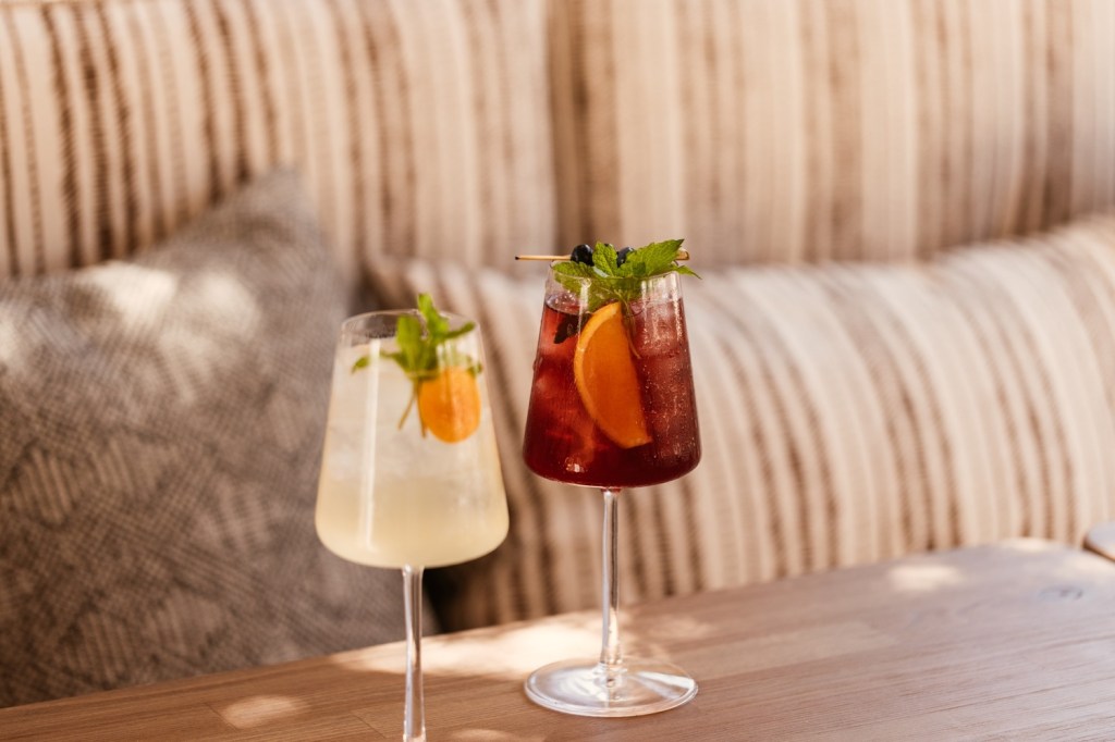 two drinks on a table, one white drink and one orange drink with a green leave in it