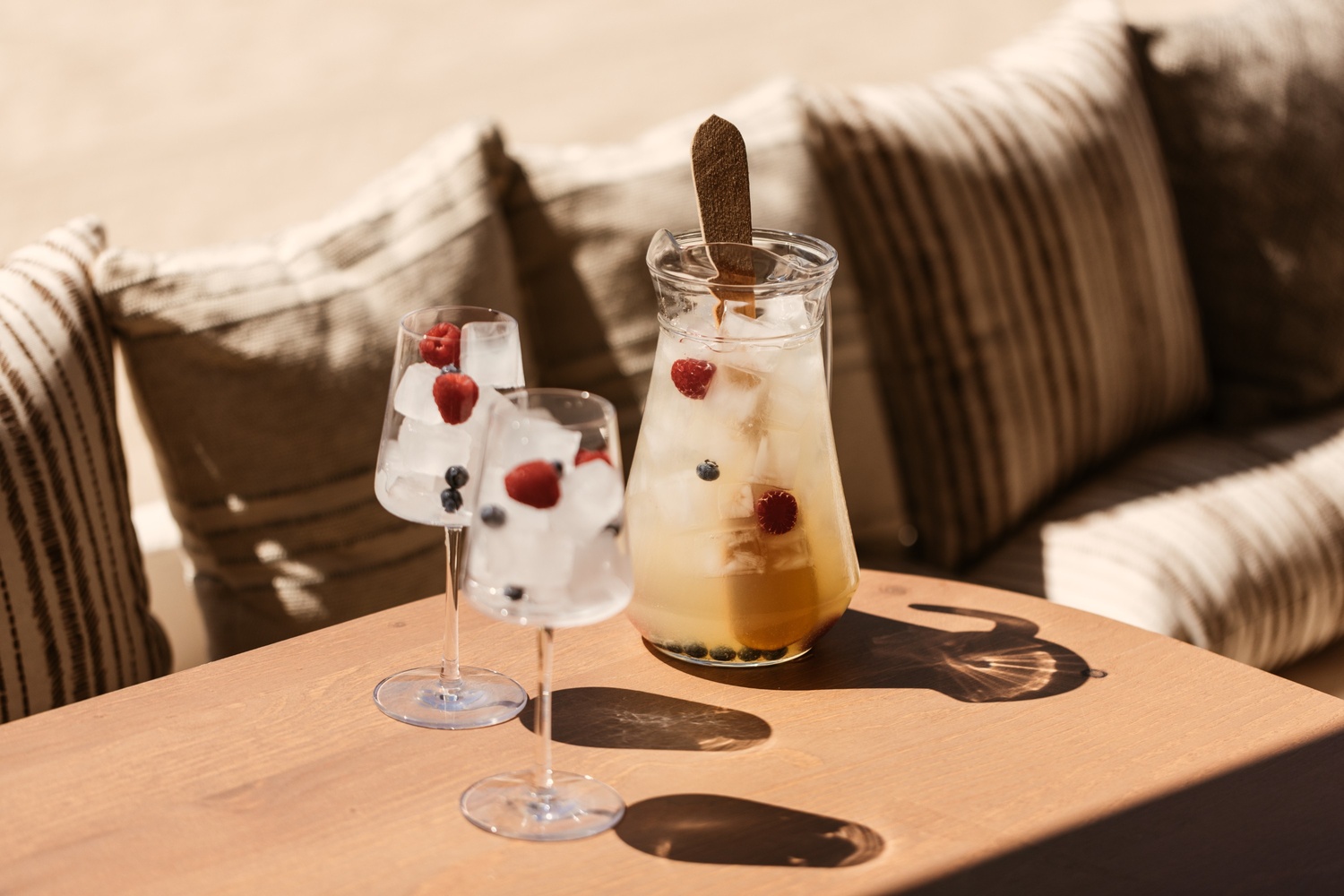 two glasses with a drink on a table with seats behind it