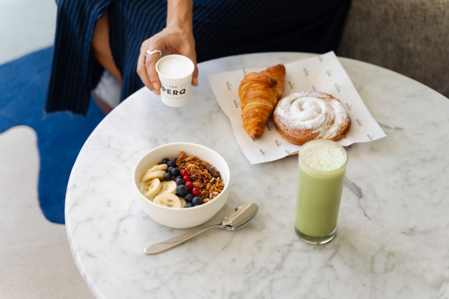 multiple breakfast options on a table with someone holding a coffee