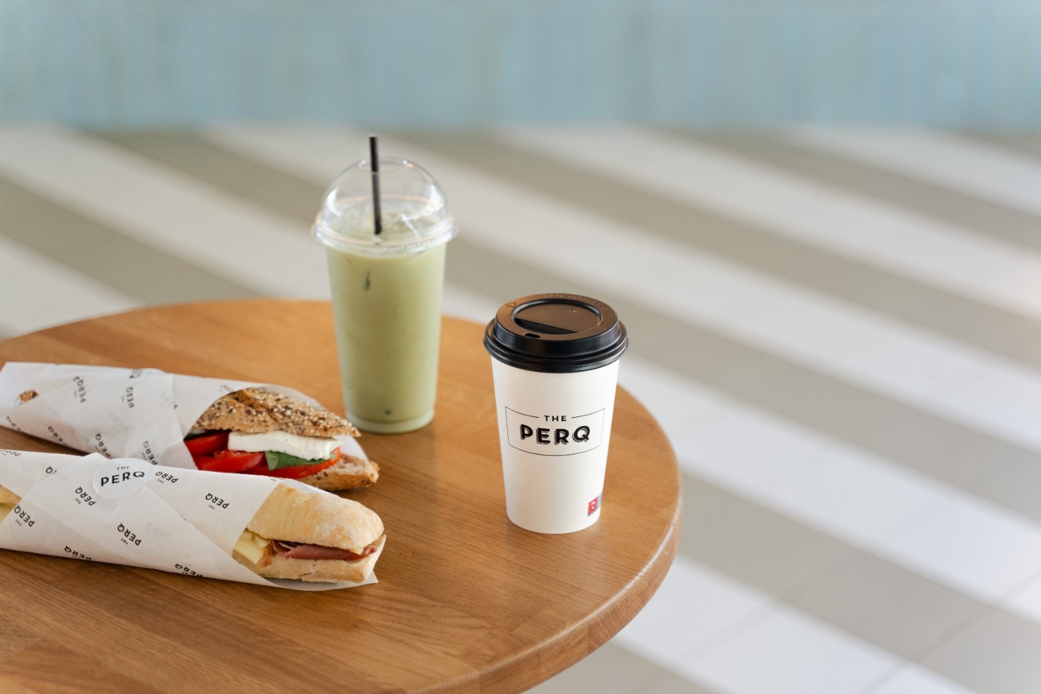 a table with two sandwiches, a coffee and a green drink on a table