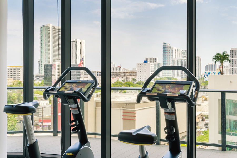 Two cross trainers facng towards the window overlooking Miami skyline at the gym at Hyde Midtown Miami