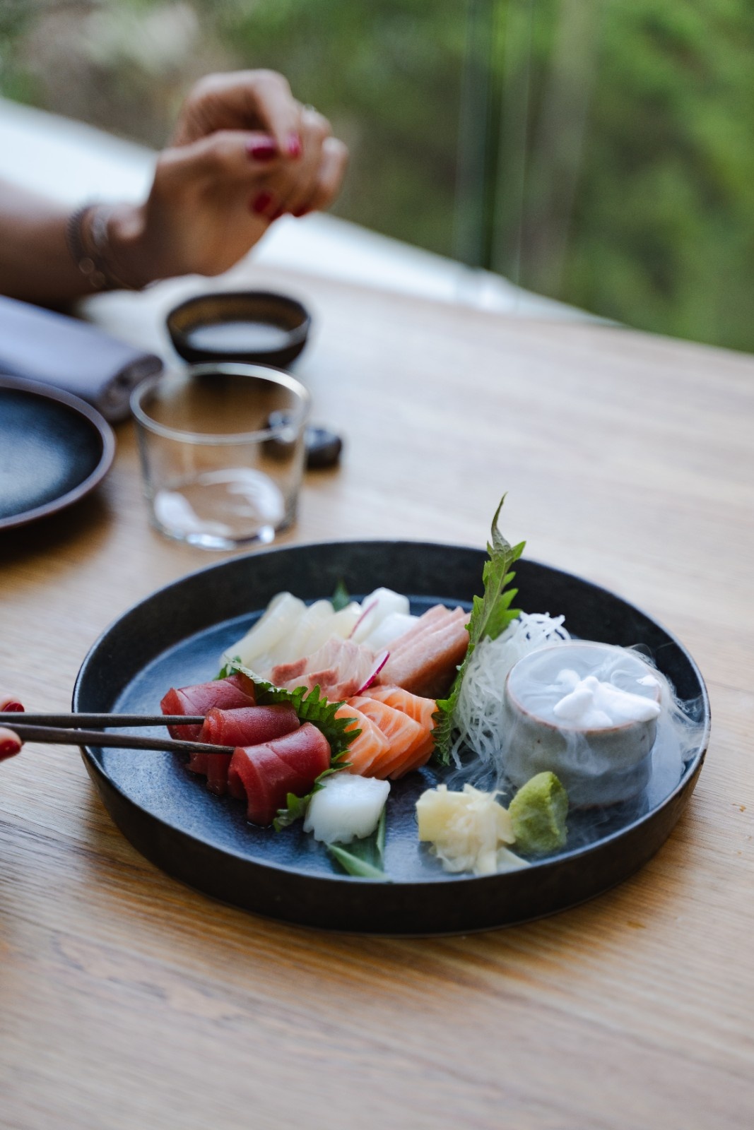 a japanese dish on a table with some chopstick showing someone digging into the meal