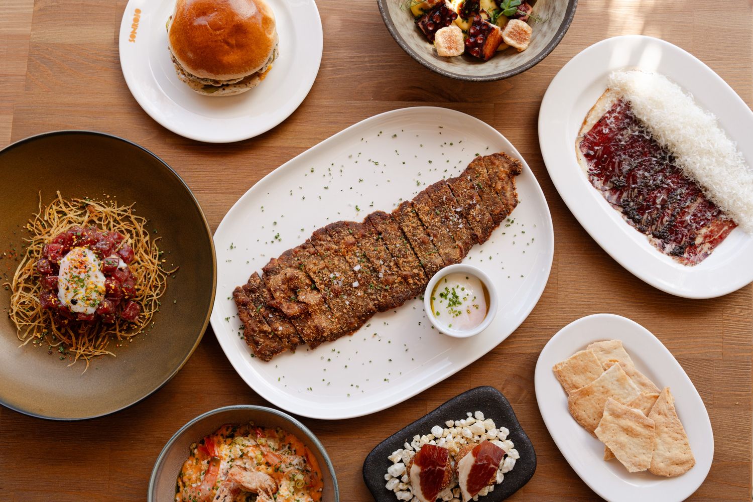 mutliple plates on a table with various food on it