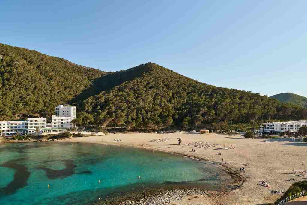 view of the beach with strunning blue waters and the hill side