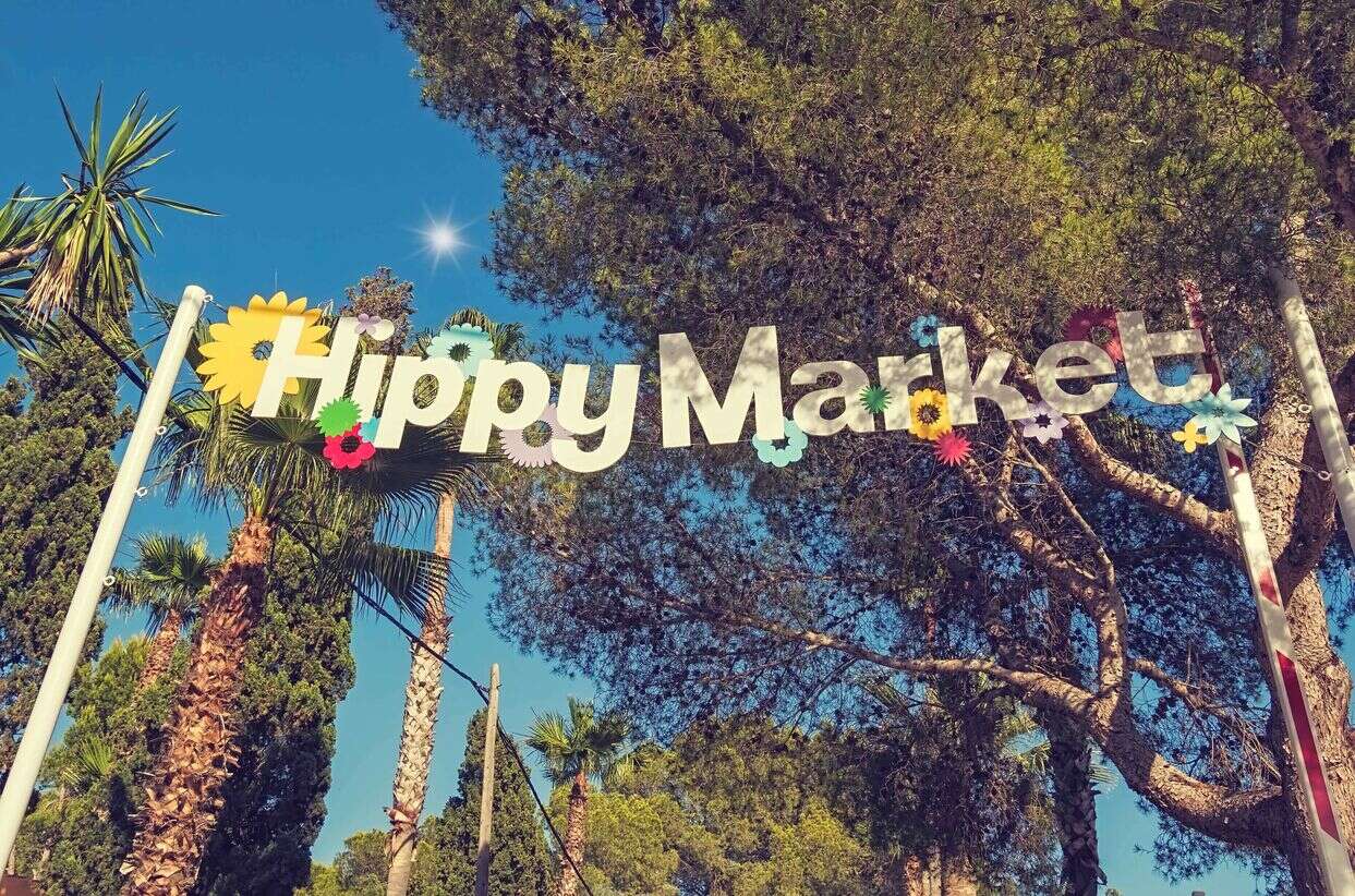 image of trees with a big sign with hippy market hanging between them