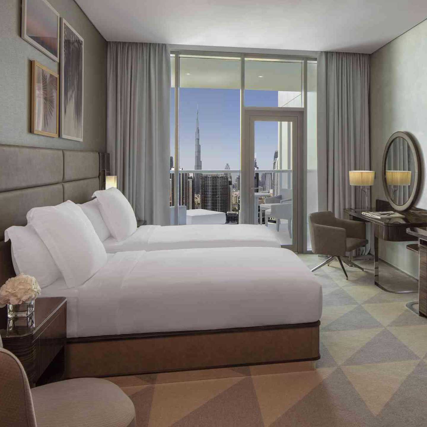A king bed at the centre, with a console table and mirror to the right, with a background view of the balcony which shows Dubai city views with Burj Khalifa building