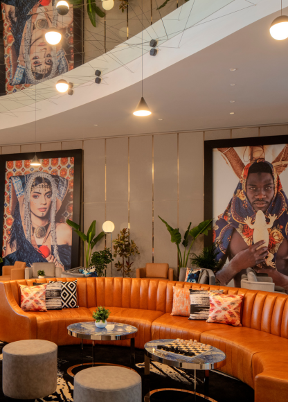 Wrap-around burnt orange leather sofa, large  framed art, and coffee tables in the lobby of Hyde Dubai