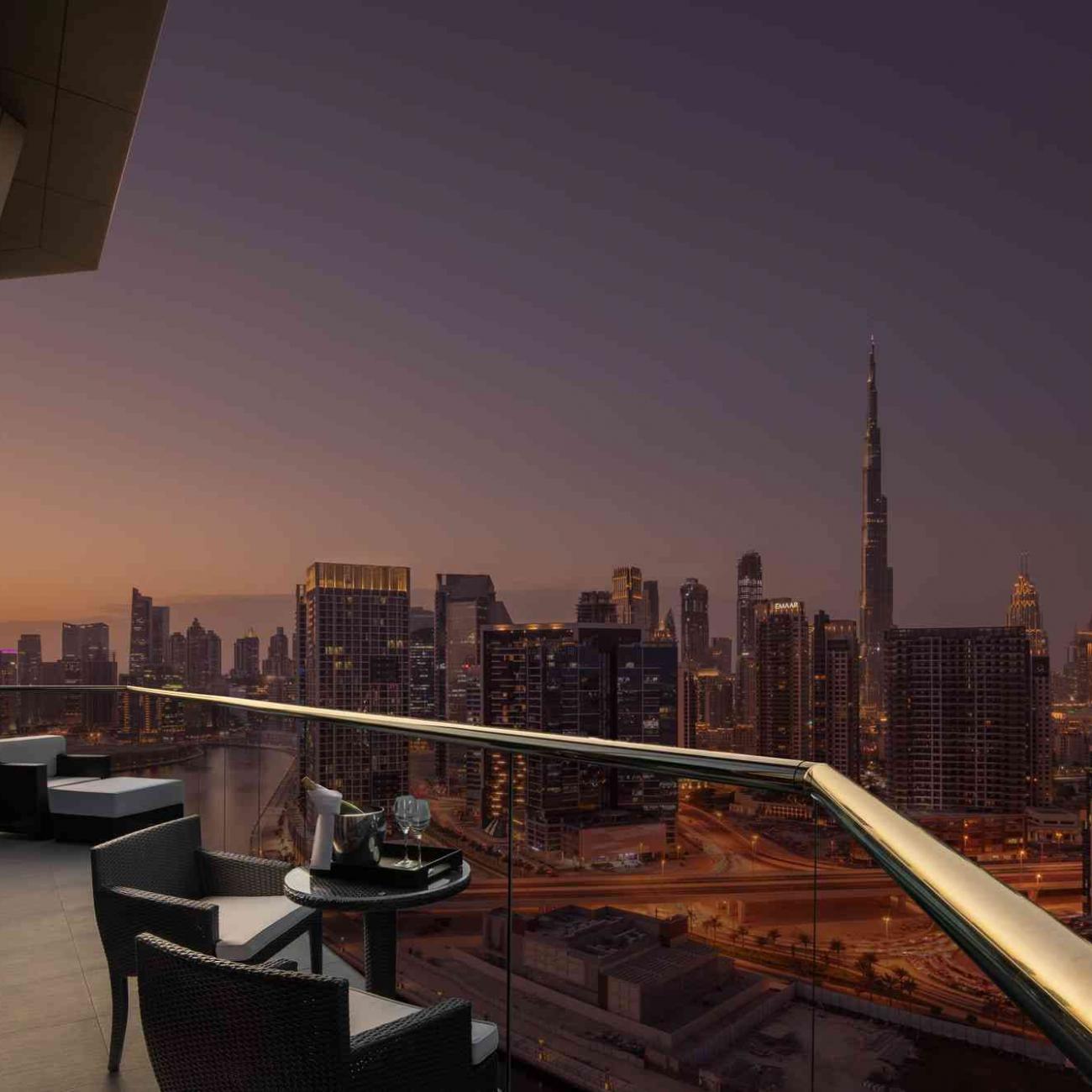 A view from the balcony displaying 2 chairs and coffee table overlooking Dubai city