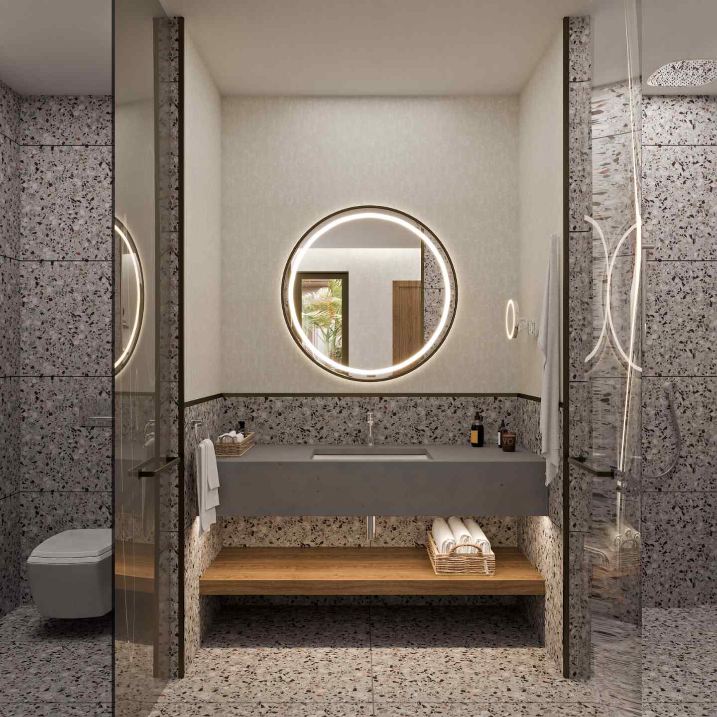 Gray marbled bathroom with large grey sink with circular lit up mirror in the center and toilet to the left, and shower to the right