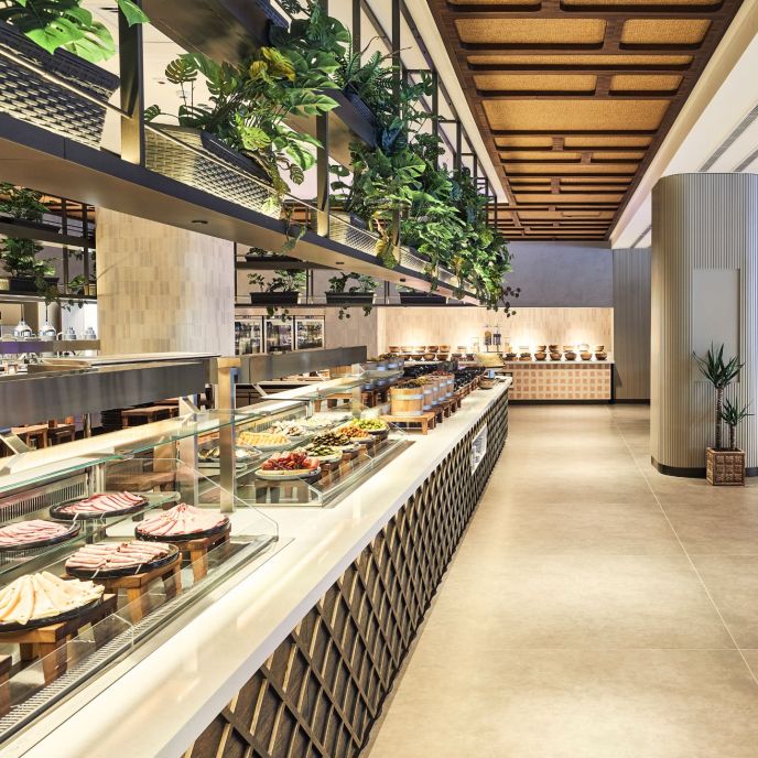 Grey dining cafeteria with Buffett of different food with plants on top