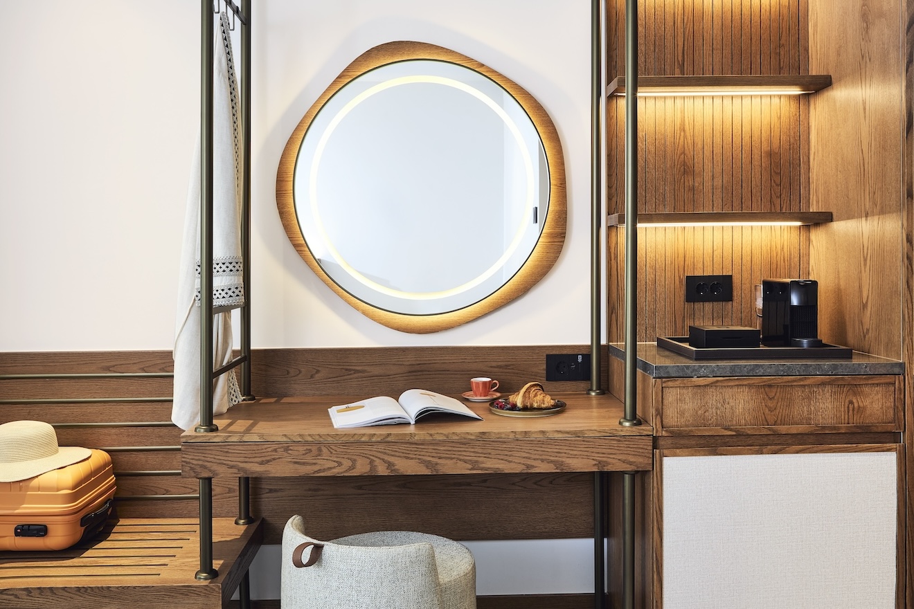 Wooden vanity with large circular mirror and wooden shelves to the right, wooden bench to the left