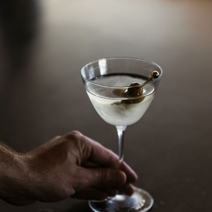 Martini with olive in a glass with hand holding glass
