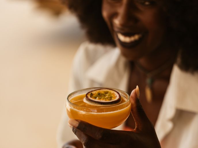 Close up of a woman smiling and holding an orange cocktail