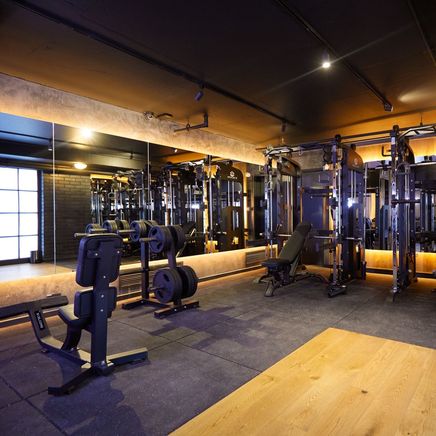 Hyde Johannesburg's indoor gym with black gym equipment, wooden floors covered with black mats, and a weights rack.